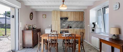 Un coin repas avec une table et des chaises en bois, une cuisine aux carreaux décoratifs et une fenêtre offrant une vue agréable.