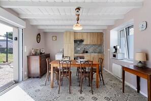 A dining area with a wooden table and chairs, a kitchen with patterned tiles, and a window with a view.