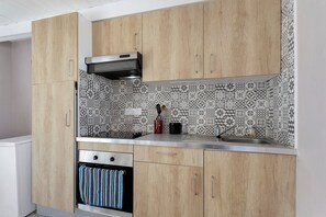 A kitchen with wooden cabinets, a stainless steel sink, and patterned backsplash.