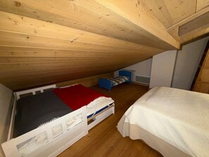 Ein kleines Schlafzimmer im Dachgeschoss mit zwei Einzelbetten, Holzwänden und einer geneigten Decke.