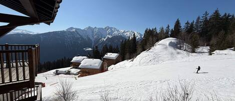 A snow-covered ski slope with a wooden building and a mountain view.