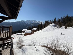 Ein mit Schnee bedeckter Skipisten mit einem Holzbau und Bergblick.