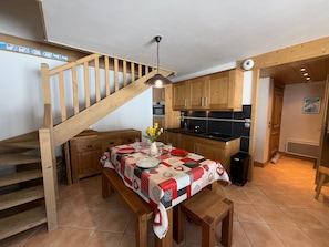 Eine Küche mit Holzausstattung, einem Esstisch mit Patchwork-Decke und einer Holztreppe.