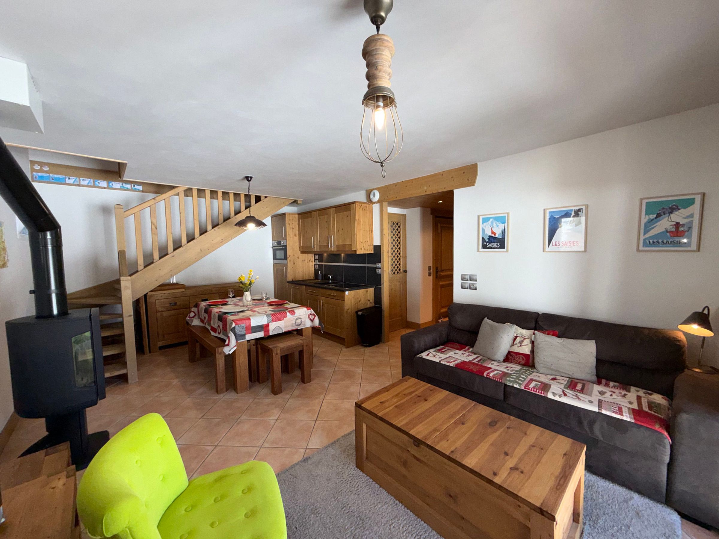 Un salon chaleureux avec un escalier en bois, un coin repas et une cuisine.