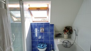 Ein Badezimmer mit Toilette, Dusche und einem Fenster.