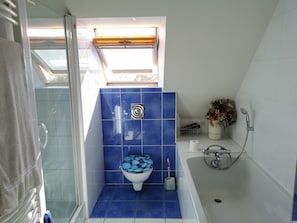 Ein Badezimmer mit Toilette, Dusche und einem Fenster.