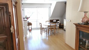 Ein Essbereich mit Holztisch und Stühlen, einer Kommode mit Lampe und Blick durch eine Glastür.