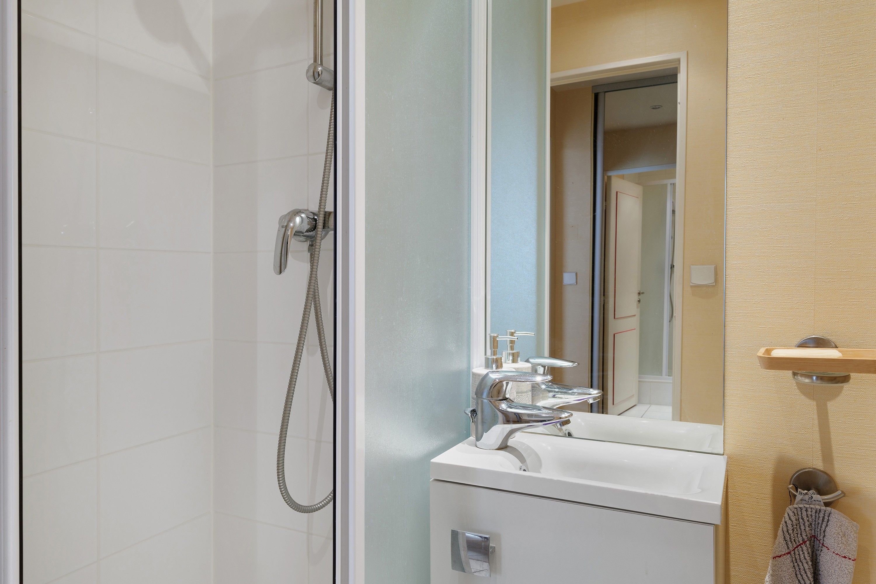 A bathroom with a glass shower enclosure, a white sink, and a mirror.