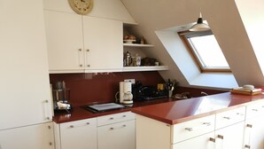 Eine Küche mit weißen Schränken, einer roten Arbeitsplatte, einer Kaffeemaschine und einem Oberlicht.