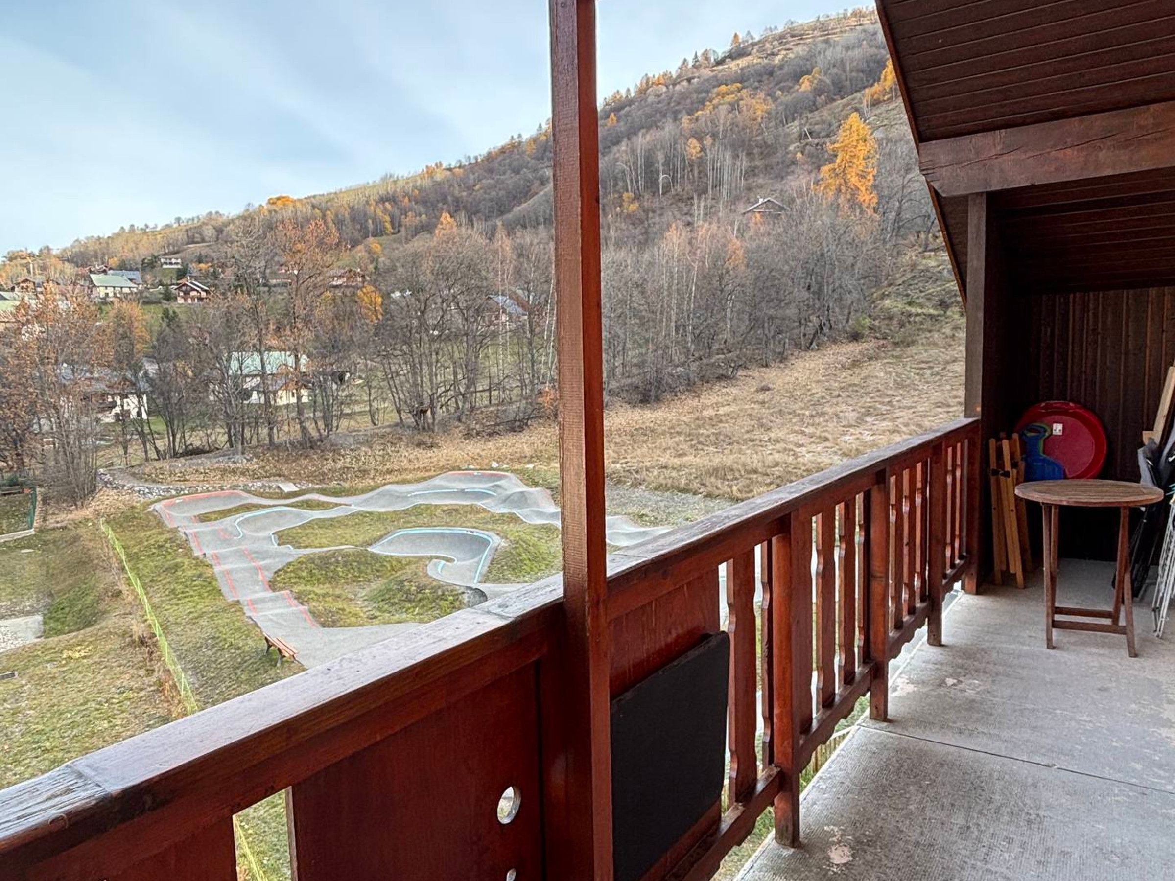Un balcon donnant sur un sentier sinueux et une colline boisée.