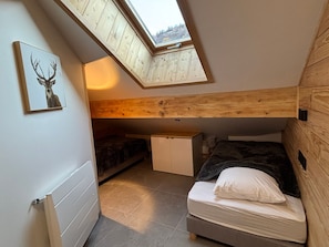 A compact bedroom with a skylight, a bed, a small cabinet, and a framed picture on the wall. - Comfortable apartment, 6 guests (Valloire)