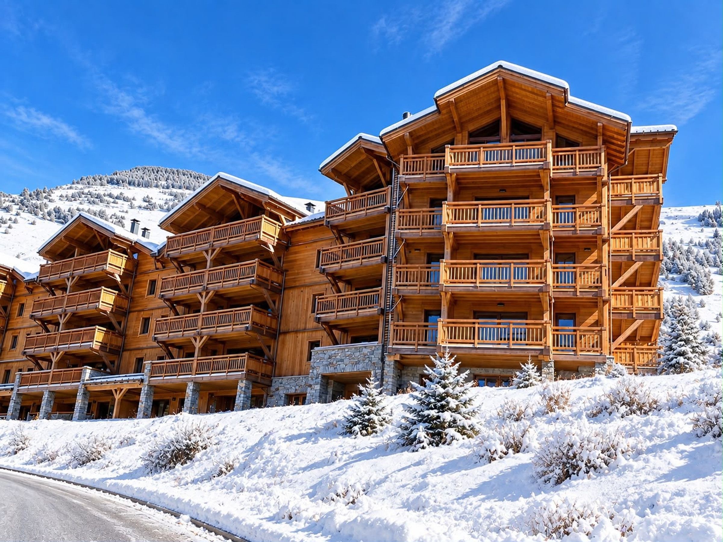 A multi-story wooden lodge with balconies, set against a snowy mountain backdrop.