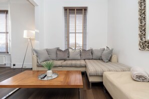 A modern living room with a sectional sofa, a wooden coffee table, and a floor lamp. - The Residences Serviced Apartments (Aberdeen)