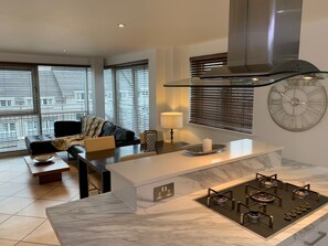 Una cocina moderna con una isla central, estufa a gas empotrada y un gran reloj de pared.