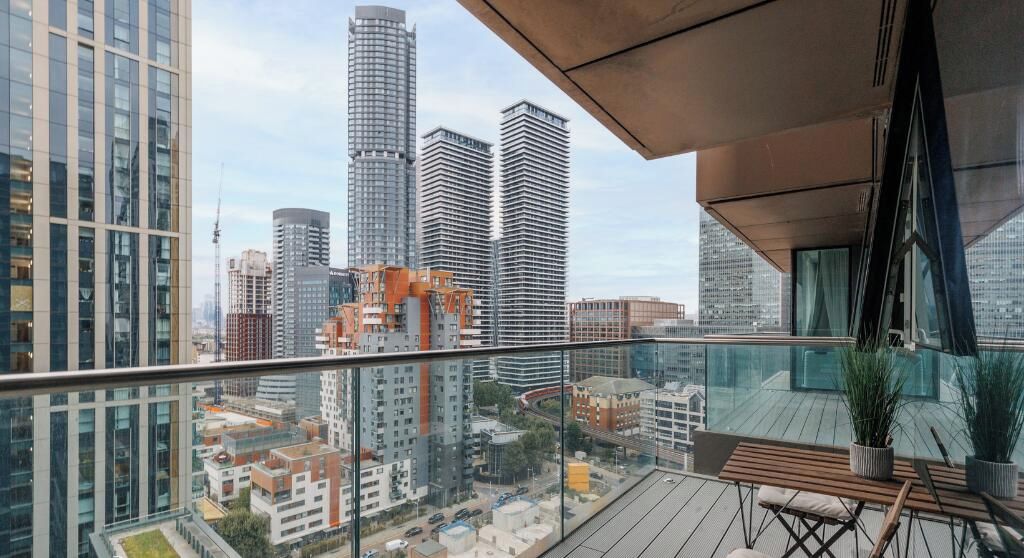 A high-rise building with a modern glass balcony overlooking a cityscape.