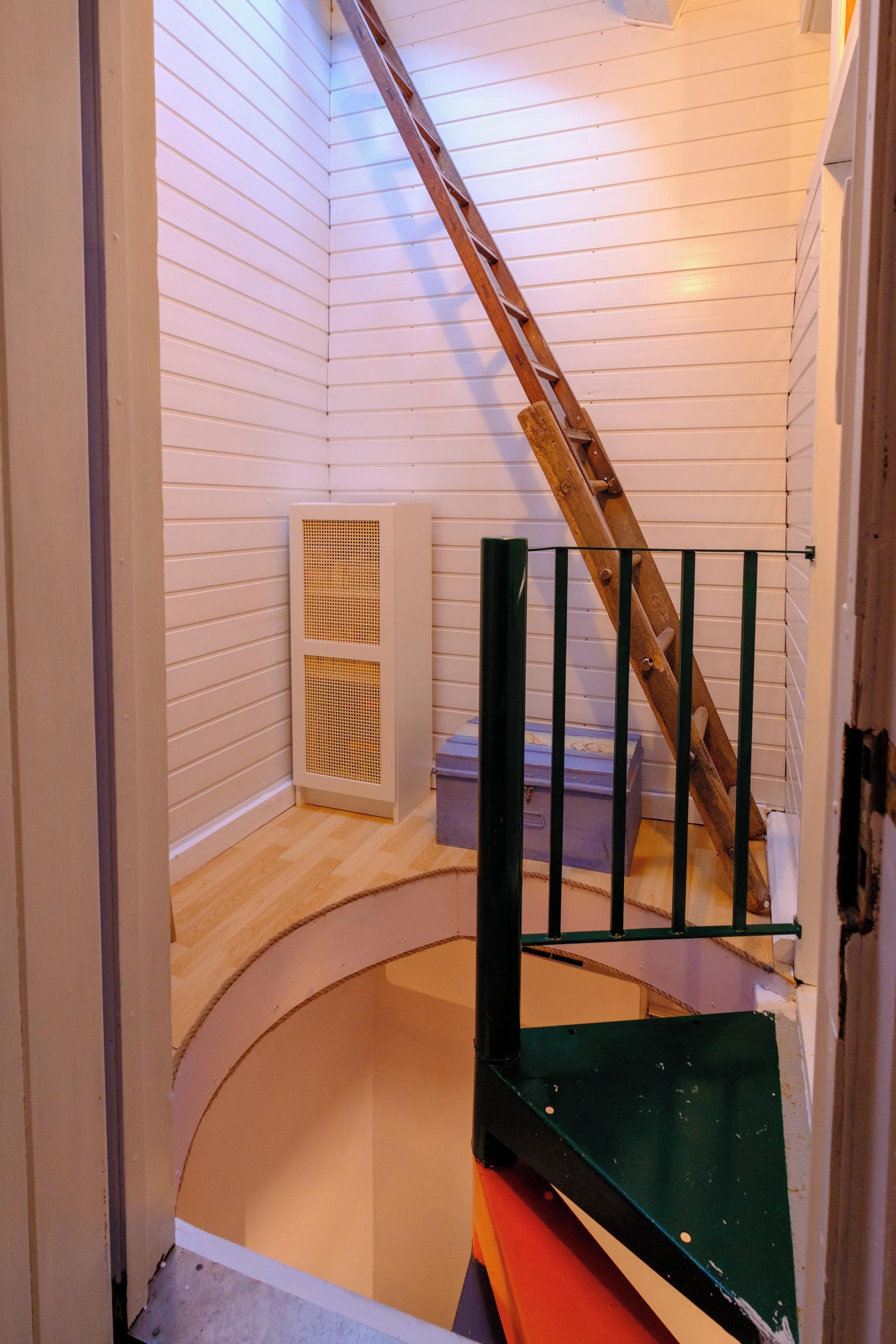Un escalier avec une rampe en bois menant à un palier doté d’un plancher en bois.