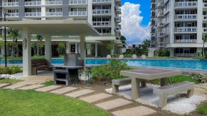 A poolside area with a covered seating area, a barbecue grill, and a pool. - 3 Bedroom Condo near BGC Taguig Alder Residences (Taguig)