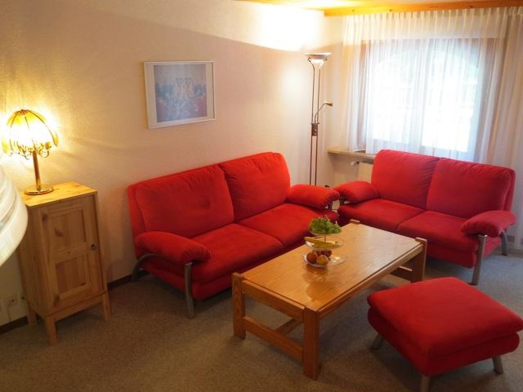Un salon avec un canapé rouge, une table basse en bois et une lampe.
