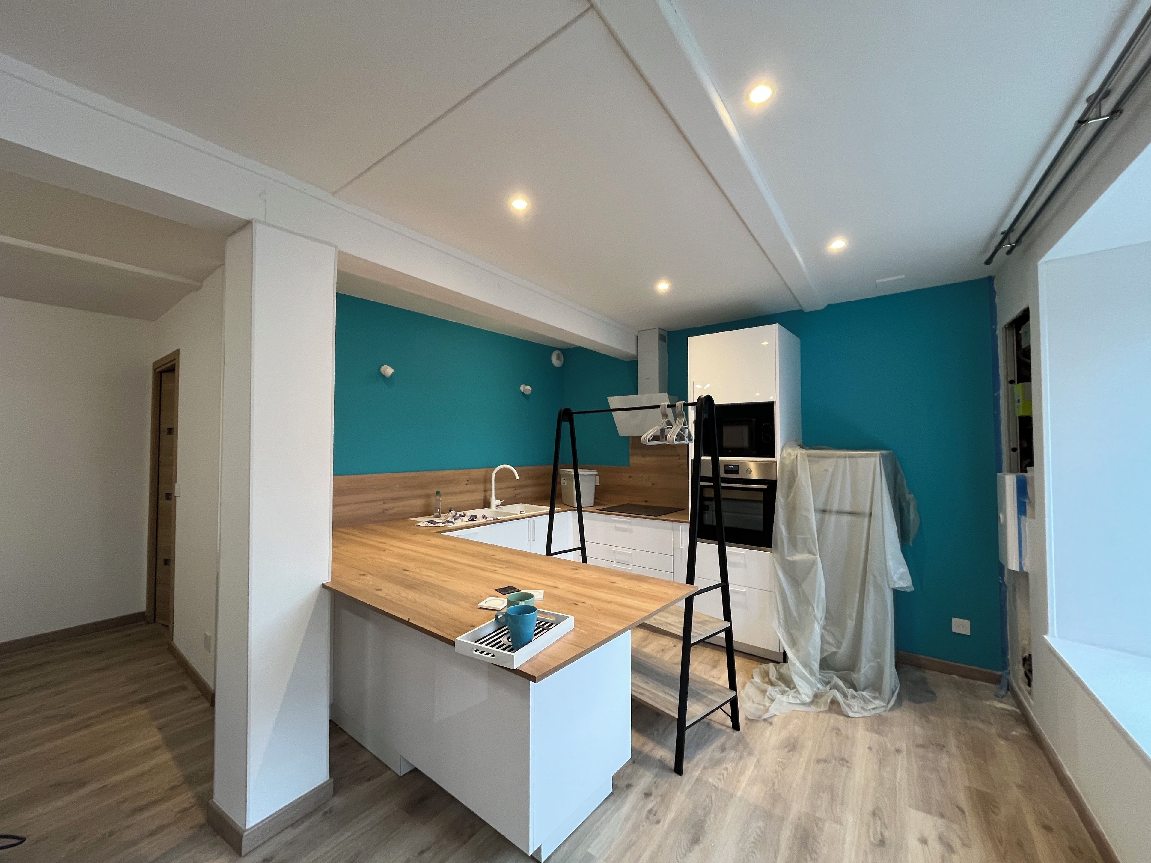 A modern kitchen with a wooden countertop, a sink, and a black metal ladder.