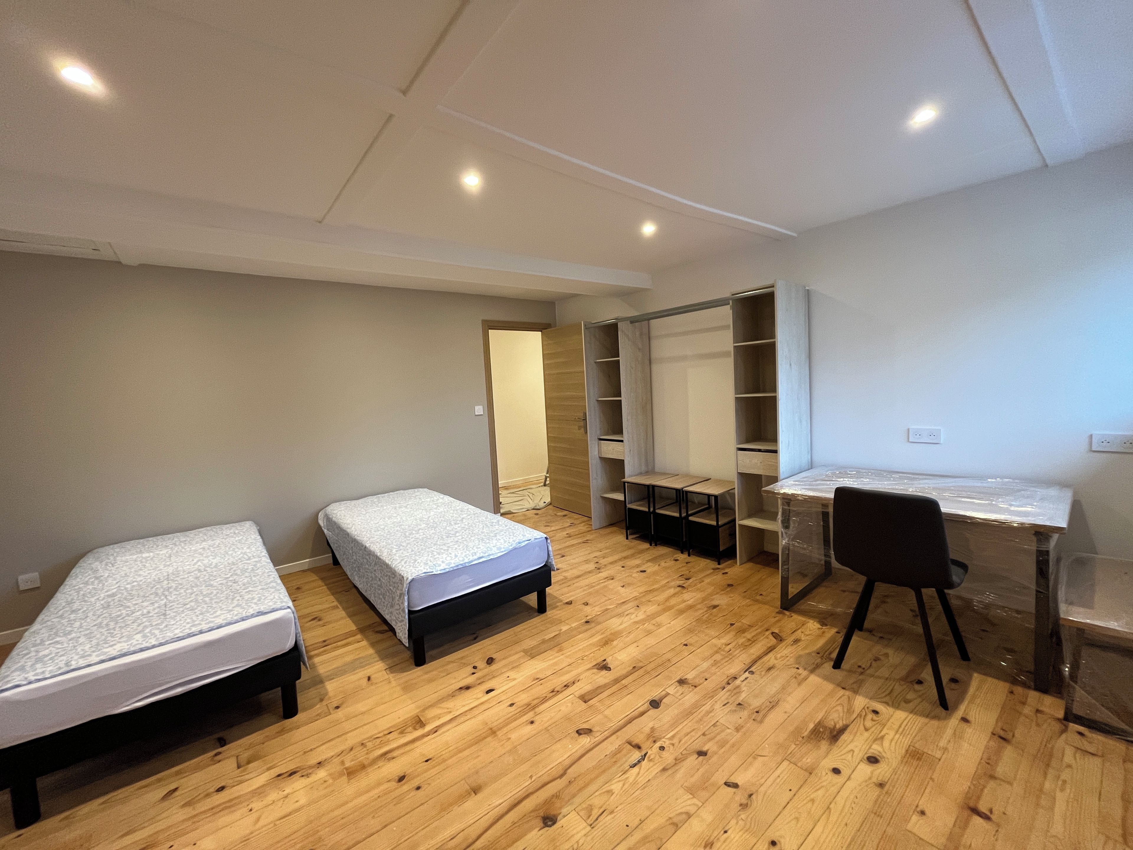 A bedroom with two single beds, a desk, and a wardrobe.