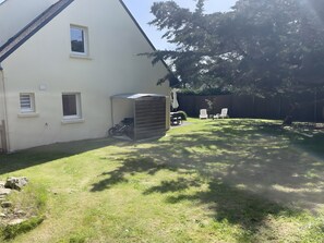 Ein Haus mit Garage, überdachter Terrasse und Rasenfläche.