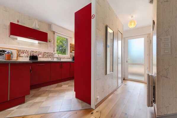 Une cuisine moderne avec des meubles de rangement rouges, un pare-feu en carrelage et un plancher en bois.