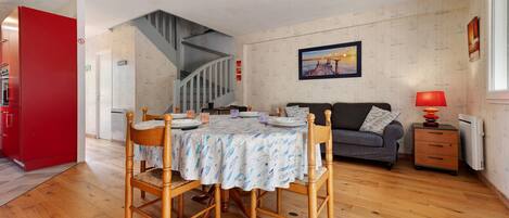 A dining area with a table set for four, a staircase, a sofa, and a red cabinet.