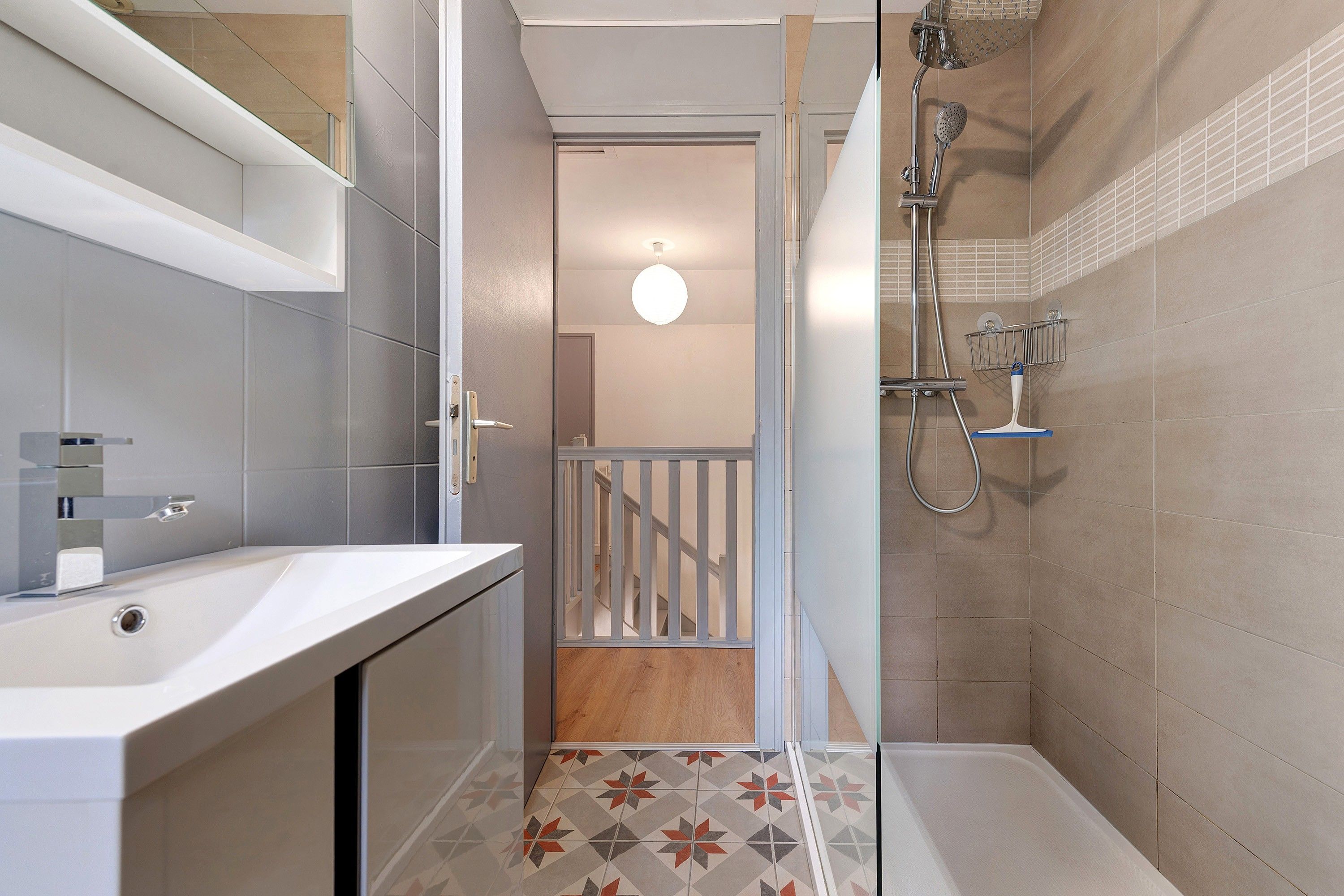 Un baño moderno con ducha, lavamanos y espejo.