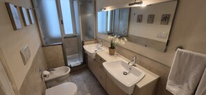A bathroom with a toilet, bidet, two sinks, a mirror, and a towel rack. - Charming 2-Bedroom San Frediano Hideaway Near the Ponte Vecchio (Firenze)