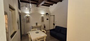 A dining area with a table and chairs, a dark-colored sofa, and pendant lighting. - Charming 2-Bedroom San Frediano Hideaway Near the Ponte Vecchio (Firenze)