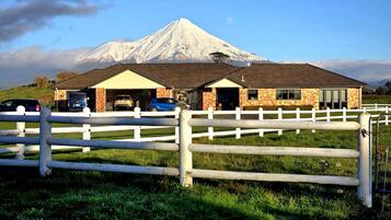 A building with a garage, a white fence, and a mountain in the background.