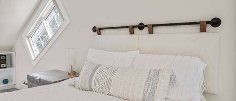 A bedroom with a bed, a nightstand, a lamp, and a window.