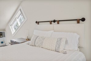 A bedroom with a bed, a nightstand, a lamp, and a window.