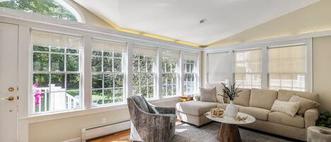 A spacious room with large windows, a sofa, a chair, and a coffee table.