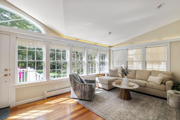 A spacious room with large windows, a sofa, a chair, and a coffee table.