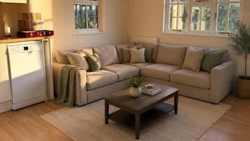 A living room with a beige sectional sofa, a coffee table, and a potted plant.
