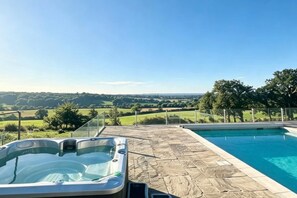 Un jacuzzi y una piscina con vistas a un paisaje verde.