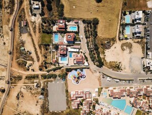 An aerial view of a resort with multiple buildings, a swimming pool, and a beach area.