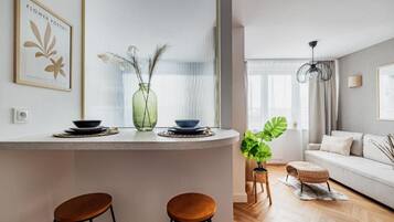 Une cuisine moderne avec un plan de travail blanc, deux tabourets et un vase contenant des plantes séchées.