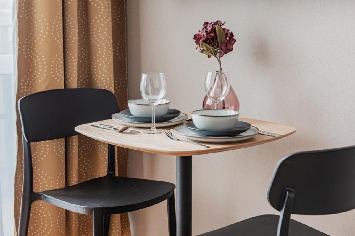 A dining table set with plates, bowls, and a vase with flowers.