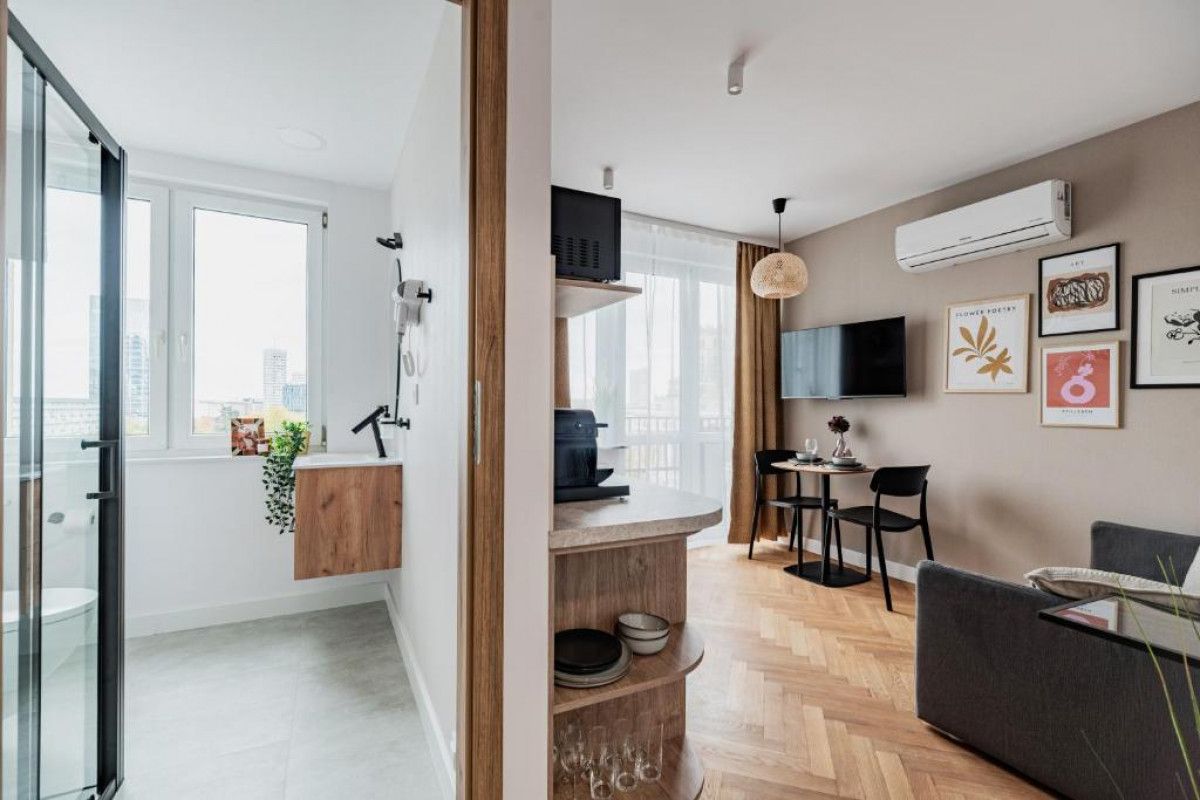 A modern living space with a kitchen area, a dining table, and a sofa.