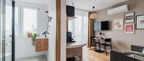 A modern living space with a kitchen area, a dining table, and a sofa.