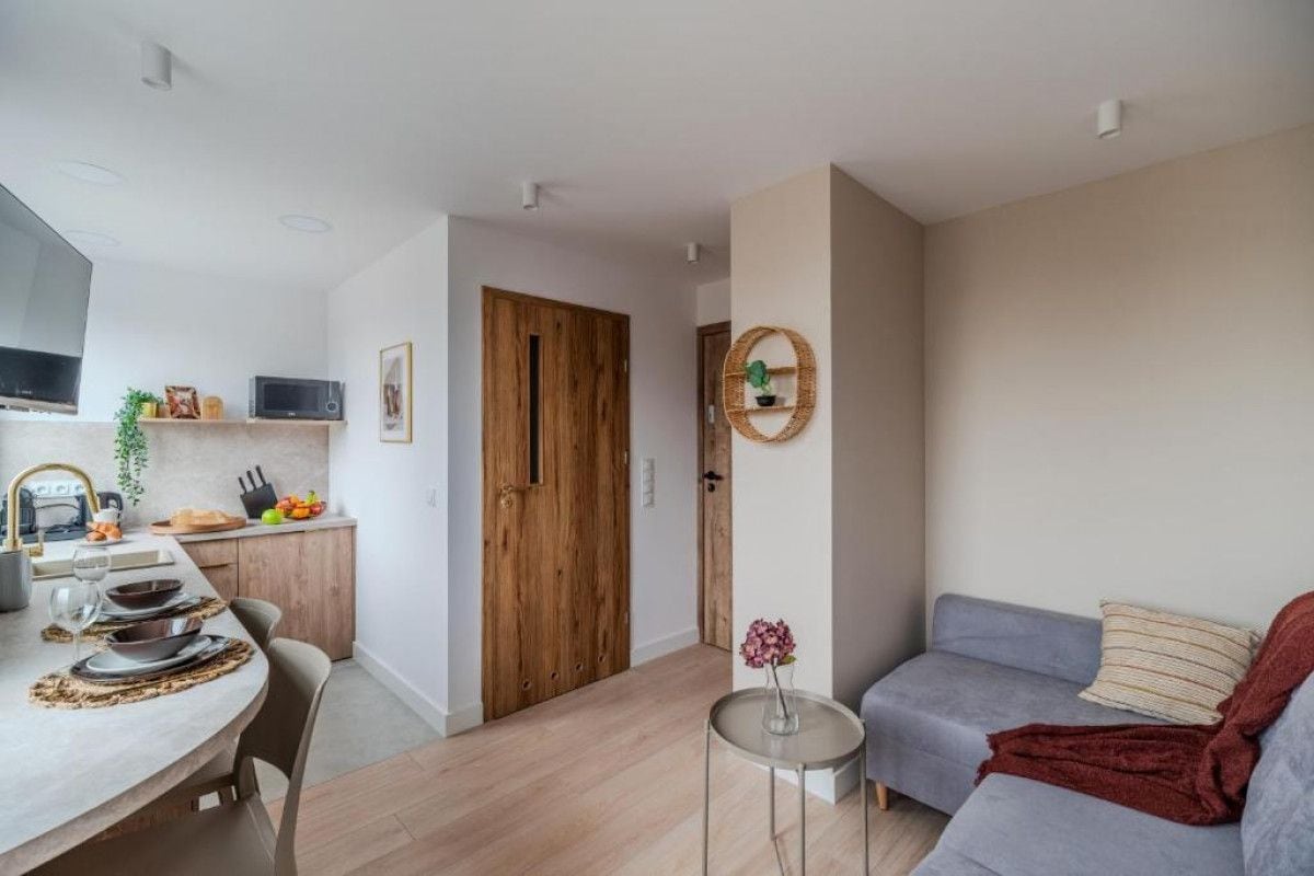 A modern living space with a dining area, a grey sofa, and a small round table with a vase.
