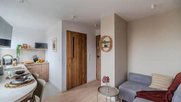 A modern living space with a dining area, a grey sofa, and a small round table with a vase.