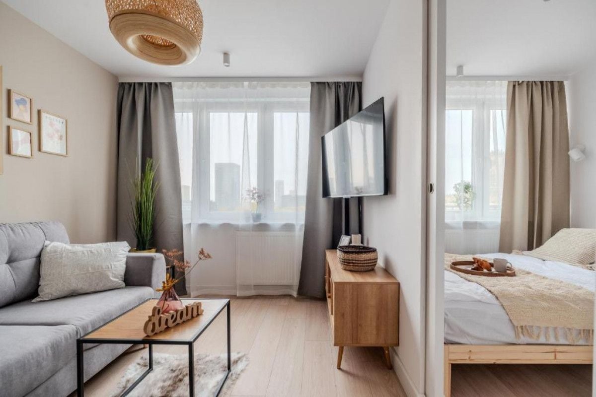 A modern bedroom with a bed, a bedside table, a television, and a window with curtains.