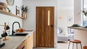 Una cocina moderna con puerta de madera, un lavamanos y una encimera con un cuenco de fruta.