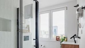 Un baño moderno con cabina de ducha de vidrio, inodoro y tocador de madera con lavamanos.