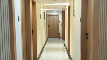 A hotel hallway with a marble floor, wooden doors, and a fire extinguisher.