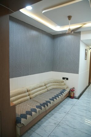 A modern interior with a sofa, a ceiling fan, and a fire extinguisher. - Hotel Harmony Inn Ahmedabad (Ahmedabad)