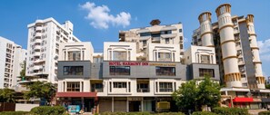 A hotel with a modern facade, multiple balconies, and a sign for 'HOTEL HARMONY INN LUNNURIOUS A.C. ROOMS'. - Hotel Harmony Inn Ahmedabad (Ahmedabad)